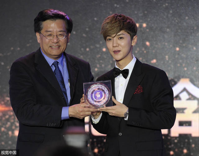 中国新闻社社长章新新（左）为年度演艺人物获奖嘉宾鹿晗颁奖。